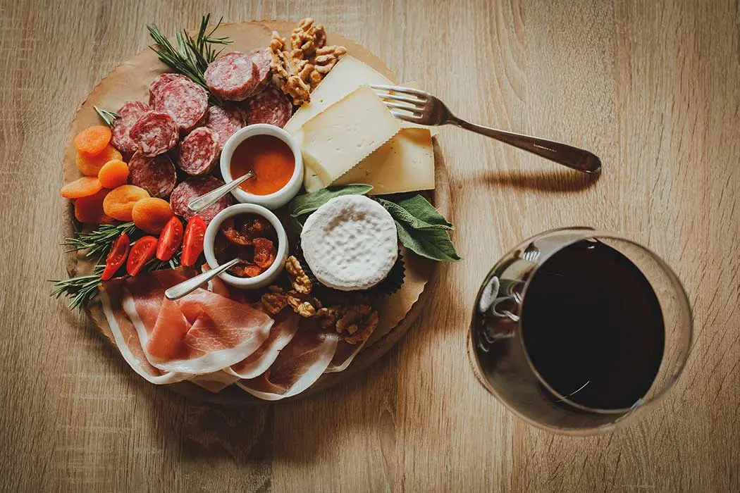 Tagliere di salumi e formaggi accompagnato da un calice di vino